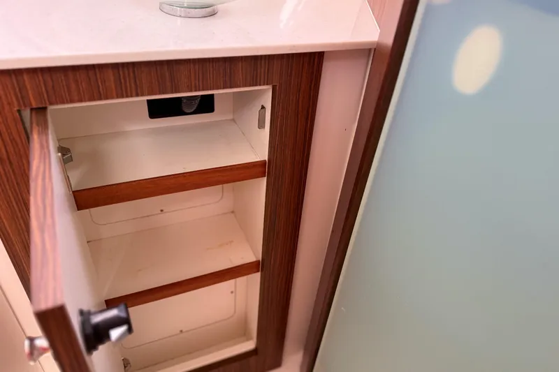 Slide: The Image of Open wooden cabinet with shelves inside a 2016 Pursuit OS 355 Offshore boat. - 44