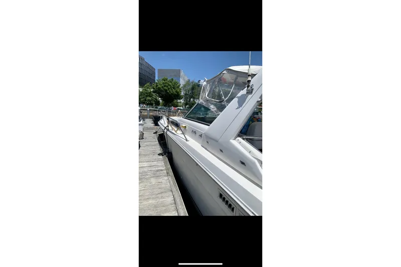 Slide: The Image of 1990 Sea Ray 350 Sundancer docked, showcasing sleek design and clear canopy under blue sky. - 2