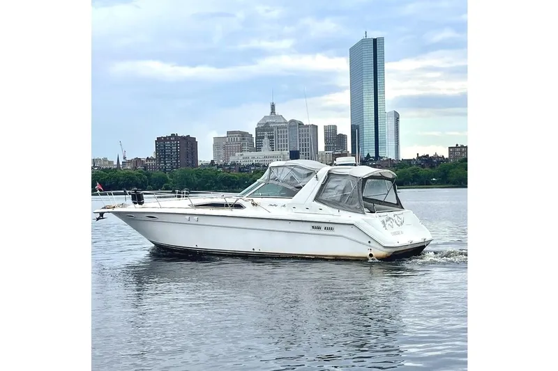 Slide: The Image of 1990 Sea Ray 350 Sundancer cruising on water with city skyline backdrop. - 5