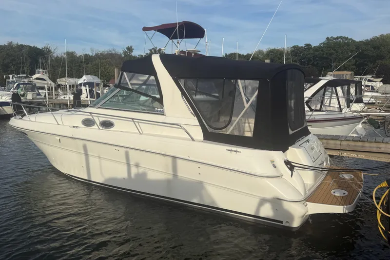 Slide: The Image of 2000 Sea Ray 310 Sundancer boat docked at marina, featuring black canopy and sleek design. - 2