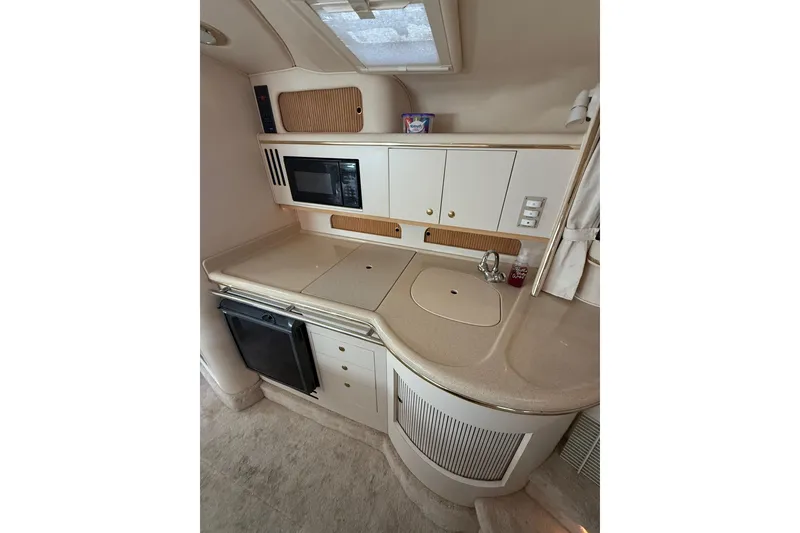 Slide: The Image of 2000 Sea Ray 310 Sundancer galley with microwave, sink, and storage cabinets. - 25