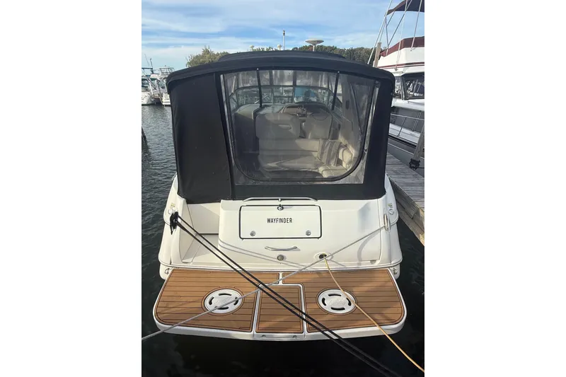 Slide: The Image of 2000 Sea Ray 310 Sundancer docked, rear view with canopy and wooden deck. - 4