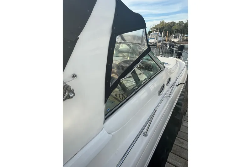 Slide: The Image of 2000 Sea Ray 310 Sundancer boat docked, featuring sleek design and black canopy. - 6