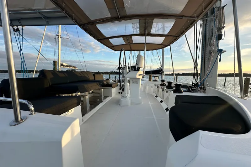 Slide: The Image of Lagoon 52 F 2021 catamaran deck with seating, under a canopy, at sunset on the water. - 14