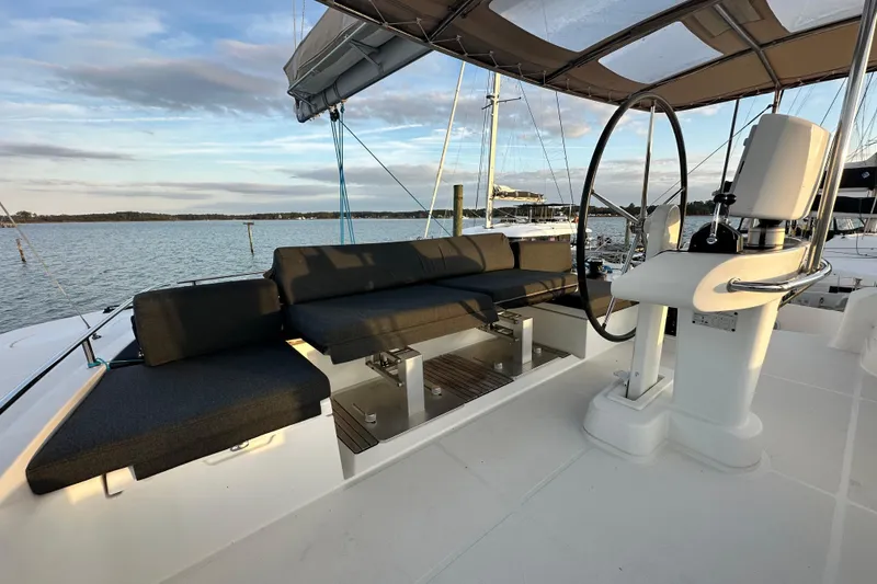 Slide: The Image of Luxurious 2021 Lagoon 52 F yacht deck with seating and steering wheel, overlooking serene waters. - 19