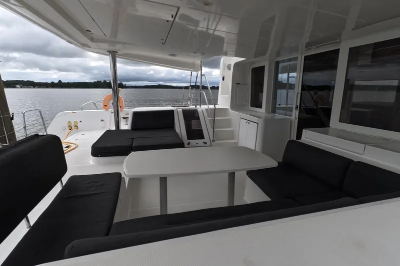 Slide: The Image of Spacious deck of 2021 Lagoon 51 catamaran with seating and table, overlooking calm waters. - 2