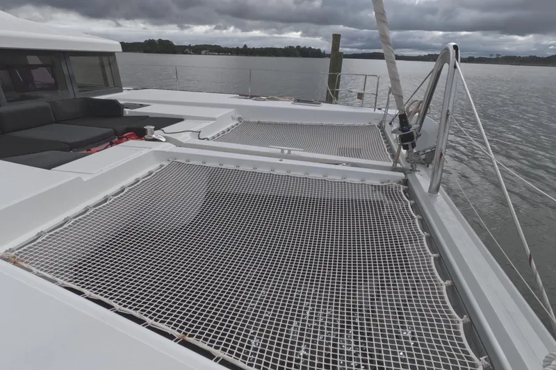 Slide: The Image of 2021 Lagoon 51 catamaran with netted deck, moored on a cloudy day. - 21