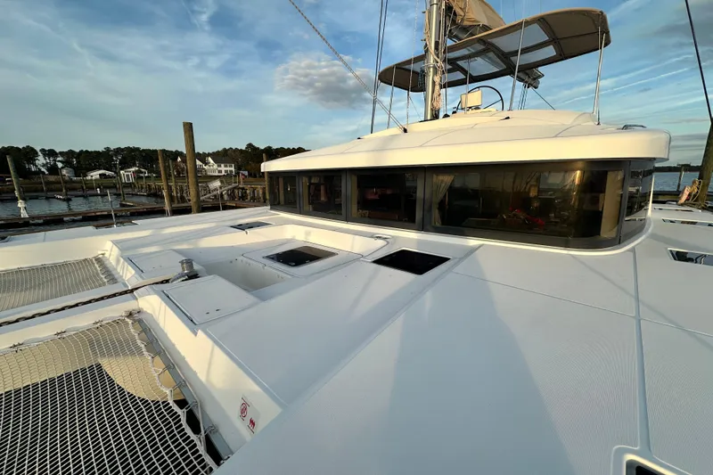 Slide: The Image of 2021 Lagoon 52 F catamaran docked, showcasing sleek design and spacious deck under clear skies. - 22