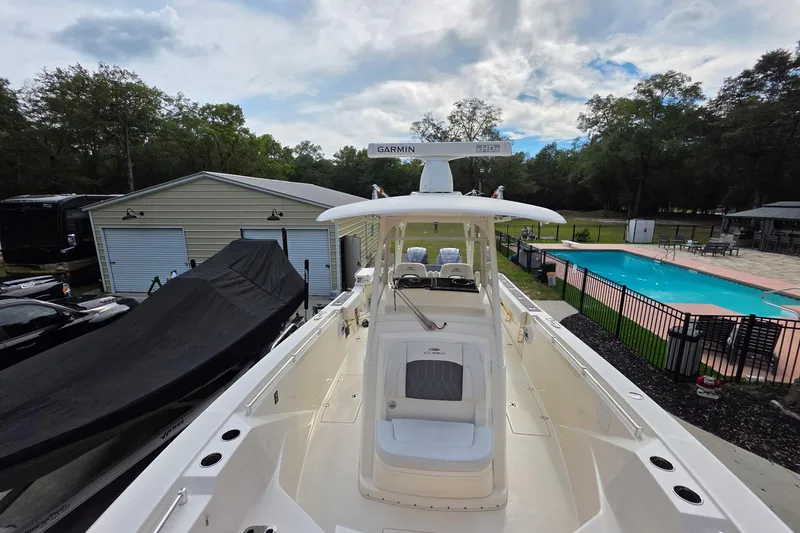 Slide: The Image of 2022 Cobia 320 Center Console boat docked near a pool and garage. - 12