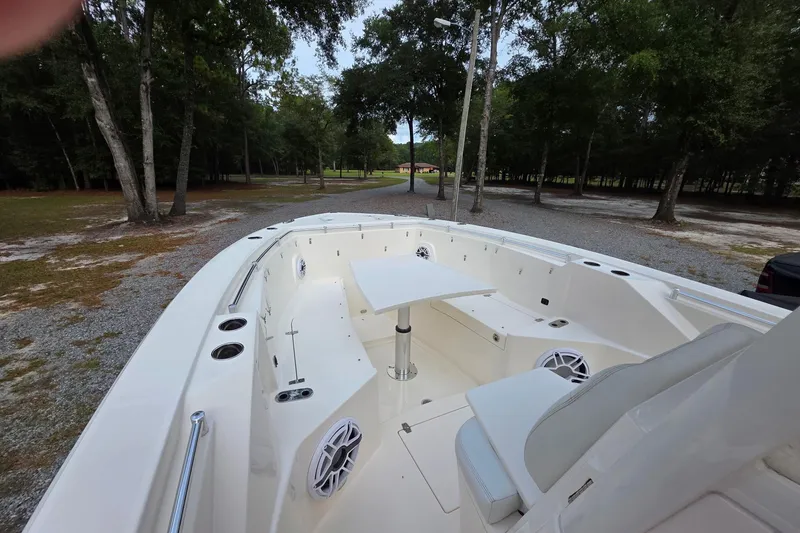 Slide: The Image of 2022 Cobia 320 Center Console boat with spacious seating and table in a wooded area. - 13
