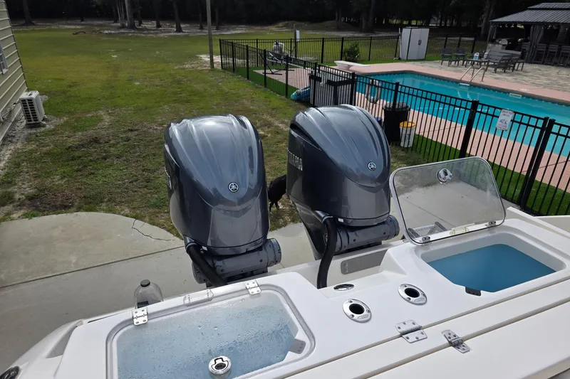 Slide: The Image of 2022 Cobia 320 Center Console boat with dual outboard engines near a pool. - 16