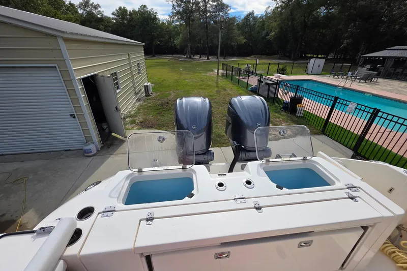 Slide: The Image of 2022 Cobia 320 Center Console boat with dual engines near a pool and garage. - 17