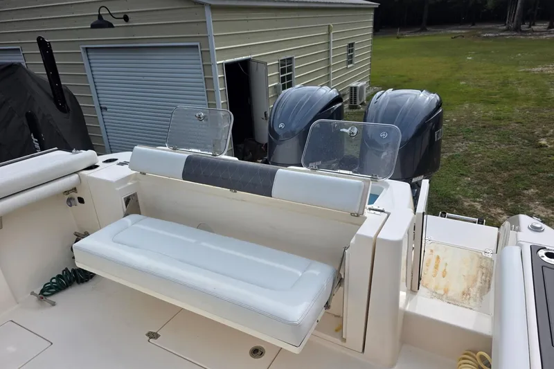 Slide: The Image of 2022 Cobia 320 Center Console boat with dual engines and seating, near a storage building. - 20