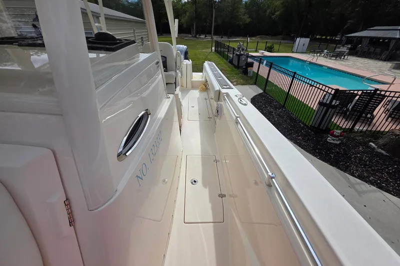Slide: The Image of 2022 Cobia 320 Center Console boat docked near a swimming pool. - 23