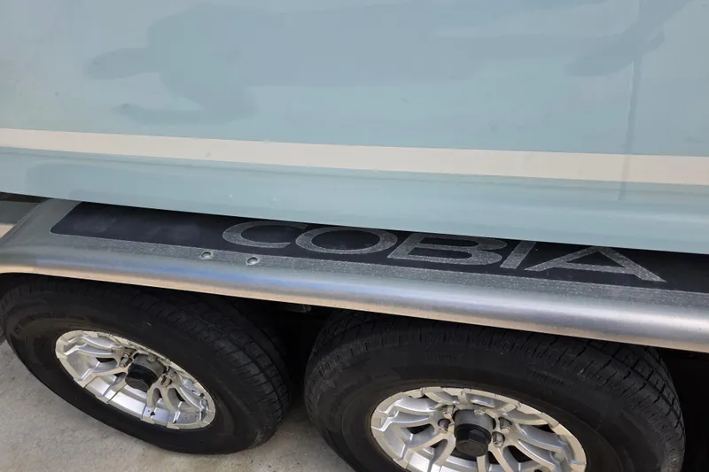 Slide: The Image of 2022 Cobia 320 Center Console boat trailer with dual wheels and logo. - 29