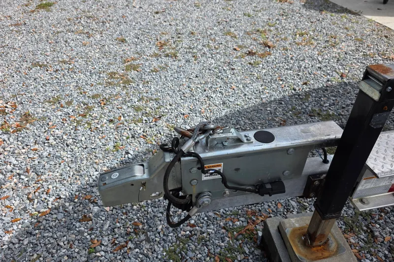 Slide: The Image of Trailer hitch of a 2022 Cobia 320 Center Console on gravel surface. - 30