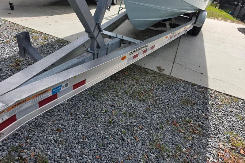 Slide: The Image of 2022 Cobia 320 Center Console boat on trailer, parked on gravel. - 32