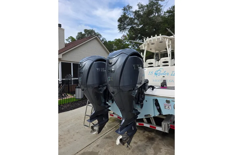 Slide: The Image of 2022 Cobia 320 Center Console with dual Yamaha outboard engines, parked on a trailer. - 4