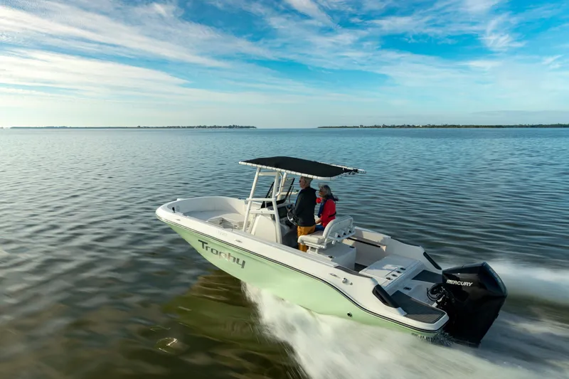 The Image of 2026 Bayliner Trophy T22CC boat cruising on open water under a clear blue sky. - 1