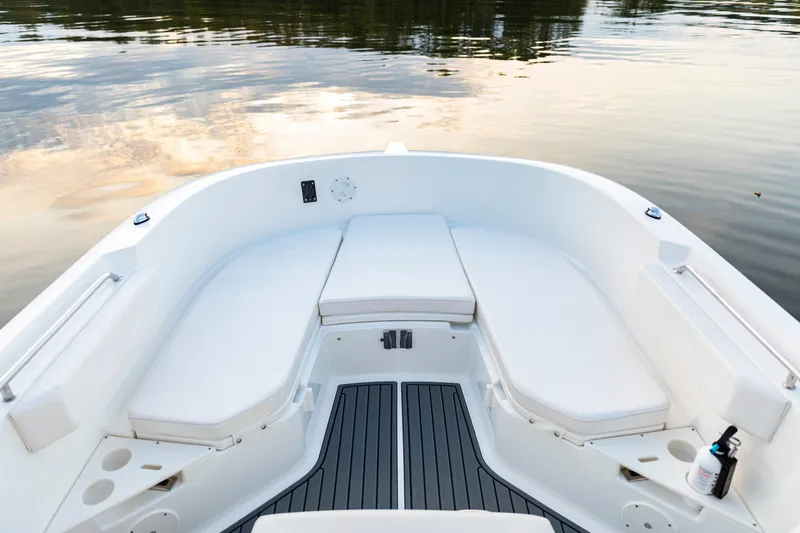 Slide: The Image of 2026 Bayliner Trophy T22CC boat interior with cushioned seating and serene water reflection. - 11