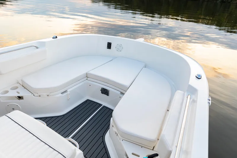 Slide: The Image of 2026 Bayliner Trophy T22CC boat interior with white seating and calm water reflection. - 13