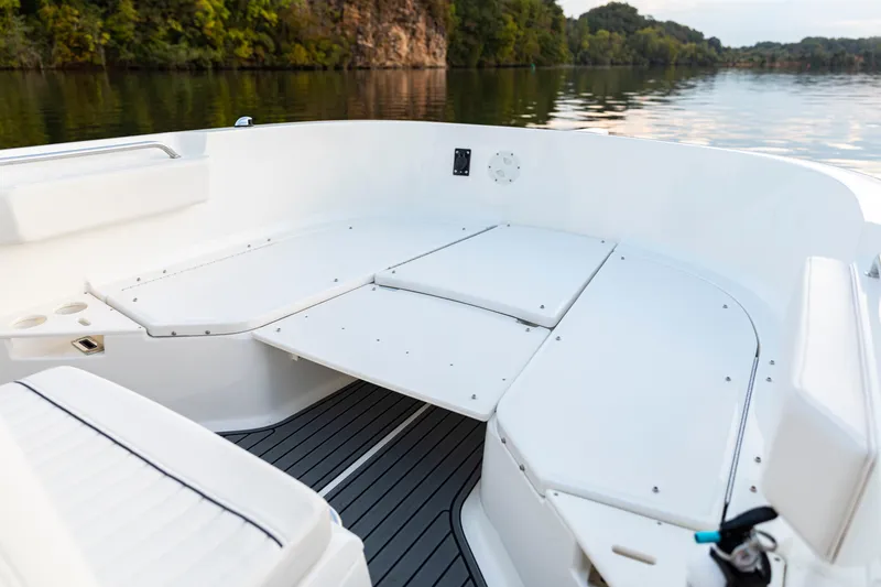 Slide: The Image of 2026 Bayliner Trophy T22CC boat interior with seating and storage, on a calm lake. - 17