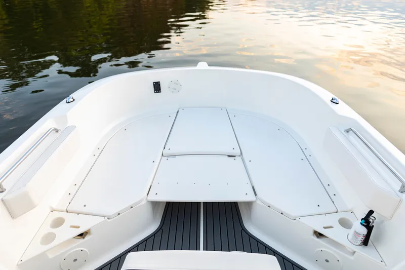 Slide: The Image of 2026 Bayliner Trophy T22CC boat interior with seating and storage, on calm water. - 19