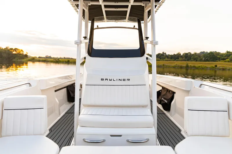 Slide: The Image of 2026 Bayliner Trophy T22CC boat interior with white seating, on a serene lake at sunset. - 24