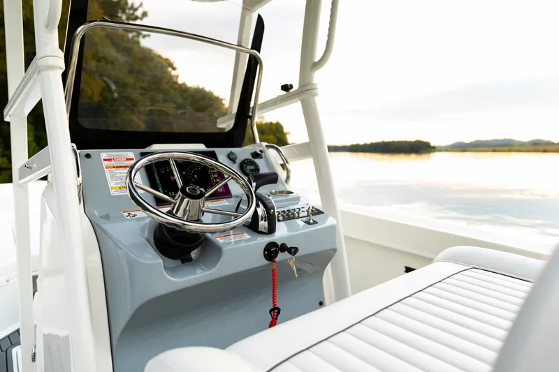 Slide: The Image of 2026 Bayliner Trophy T22CC boat dashboard with steering wheel and controls, overlooking serene water. - 44