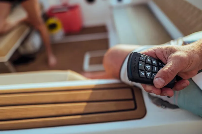 Slide: The Image of Hand holding remote control on 2026 Bayliner Trophy T22SC boat interior. - 15