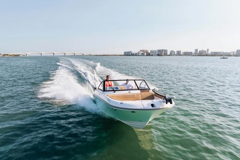 Slide: The Image of 2026 Bayliner Trophy T22SC cruising on open water near a city skyline. - 22