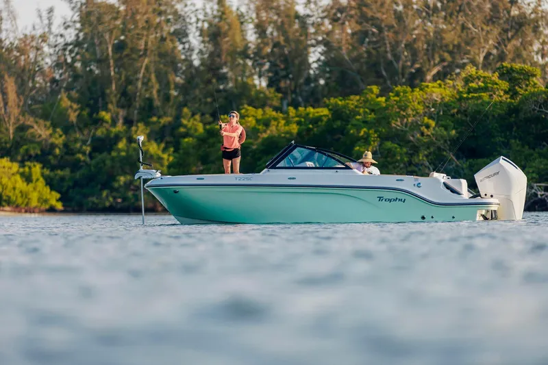 Slide: The Image of 2026 Bayliner Trophy T22SC boat on water, people fishing, lush greenery background. - 24