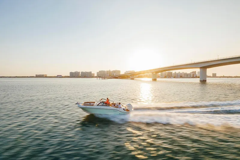 Slide: The Image of 2026 Bayliner Trophy T22SC boat cruising under a bridge at sunset. - 37