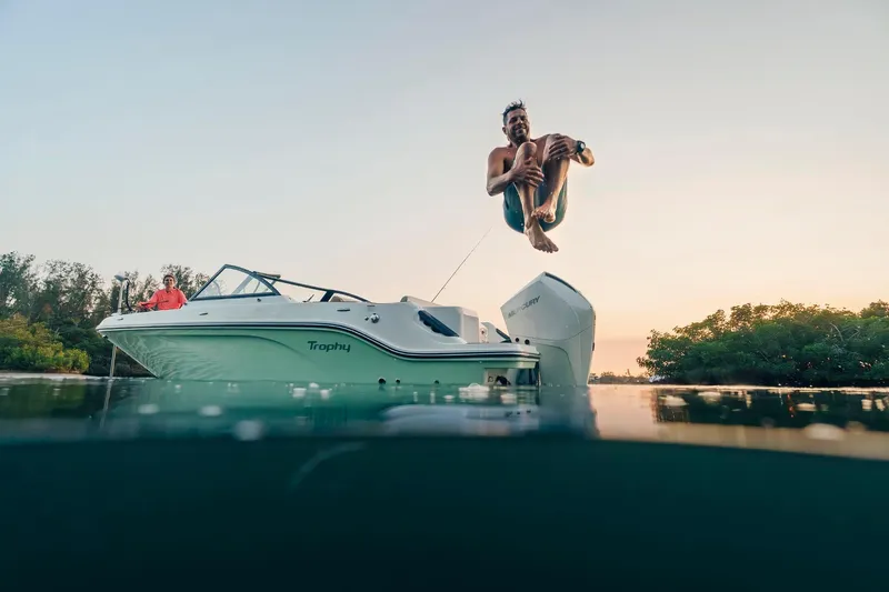 Slide: The Image of Man jumping off 2026 Bayliner Trophy T22SC boat at sunset, enjoying water adventure. - 44