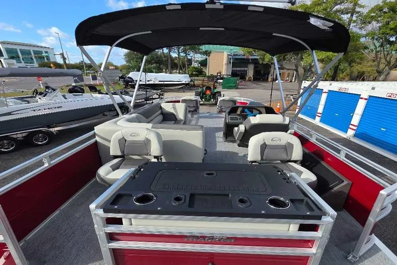 Slide: The Image of 2026 Sun Tracker Fishin' Barge 22 DLX pontoon boat with seating and canopy, parked outdoors. - 2