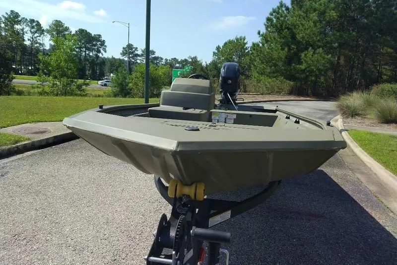 Slide: The Image of 2026 Tracker Grizzly 1648 SC boat on trailer, parked outdoors, surrounded by trees. - 4