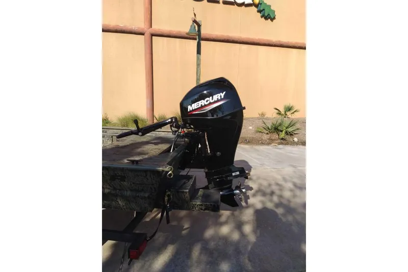 Slide: The Image of 2026 Tracker Grizzly 1654 T Sportsman with Mercury outboard motor, parked outdoors. - 43