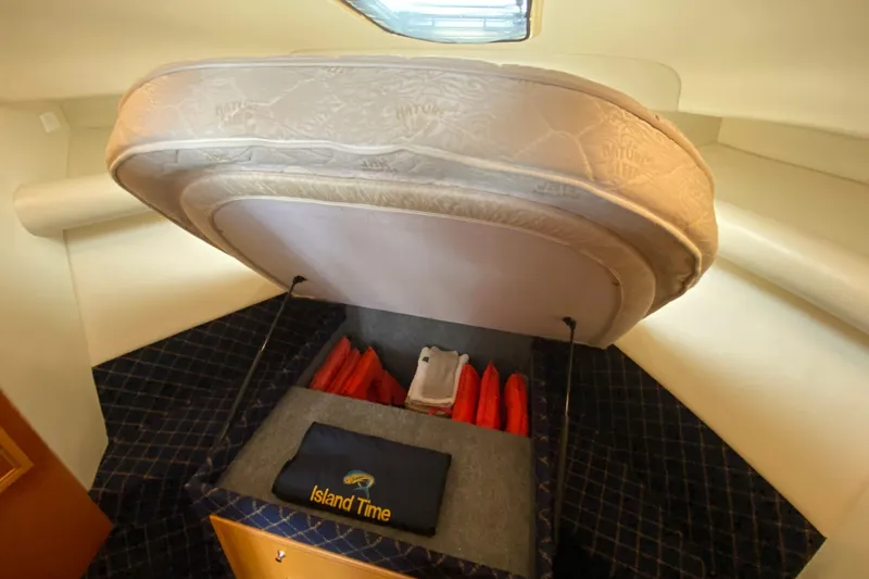 Slide: The Image of Under-bed storage in 2000 Riviera 4000 boat, featuring life jackets and "Island Time" towel. - 51