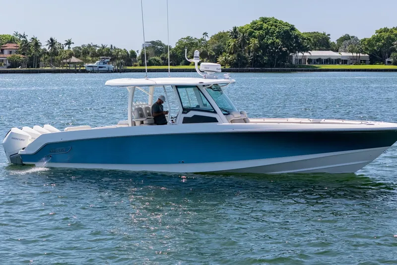 Slide: The Image of 2022 Boston Whaler 380 Outrage boat cruising on a sunny day, surrounded by lush greenery. - 18
