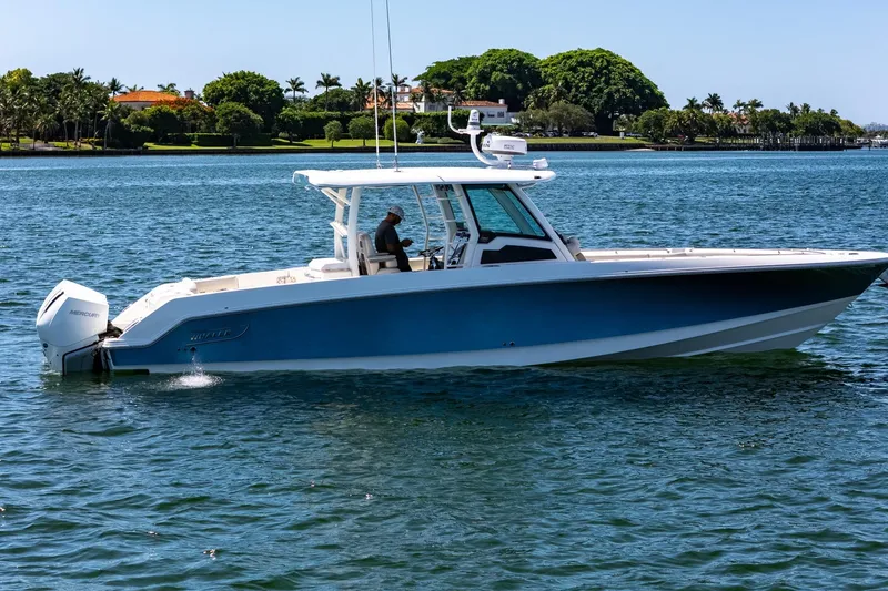 Slide: The Image of 2022 Boston Whaler 380 Outrage boat cruising on a sunny day near lush shoreline. - 19