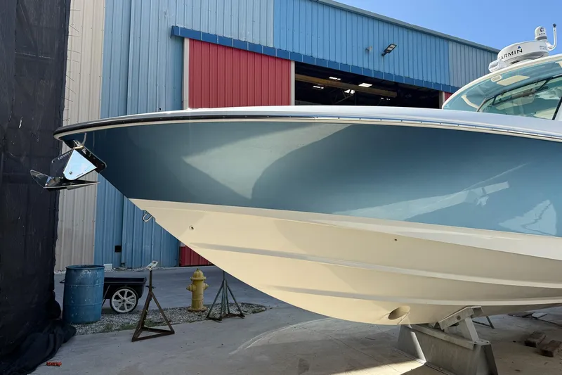 Slide: The Image of 2022 Boston Whaler 380 Outrage boat docked near a blue and red building. - 41