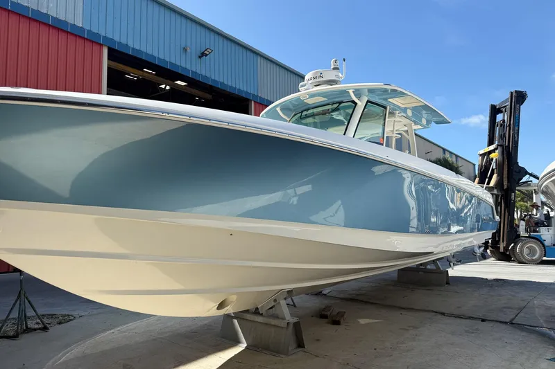 Slide: The Image of 2022 Boston Whaler 380 Outrage boat in a marina, showcasing sleek design and blue hull. - 42