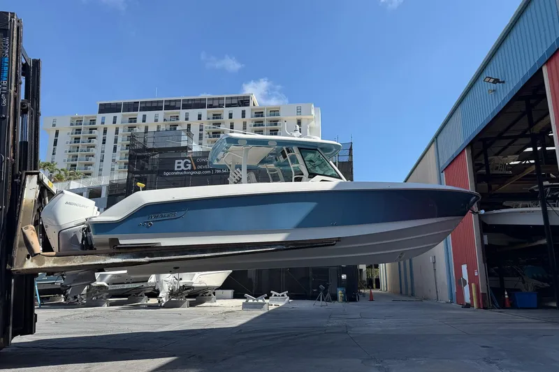 Slide: The Image of 2022 Boston Whaler 380 Outrage boat lifted in marina, urban backdrop. - 45