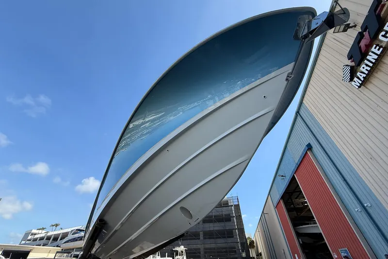 Slide: The Image of 2022 Boston Whaler 380 Outrage boat hull, viewed from below, near a marine facility. - 46