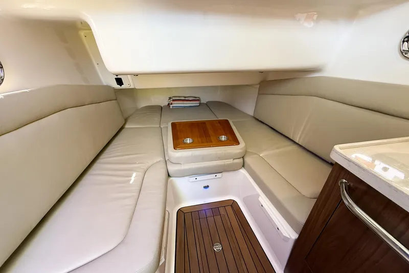 Slide: The Image of 2022 Boston Whaler 380 Outrage cabin interior with cushioned seating and wooden table. - 53