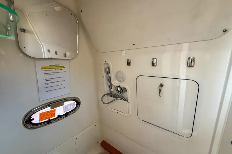 Slide: The Image of Interior of 2022 Boston Whaler 380 Outrage, featuring a compact bathroom with mirror and shower. - 59