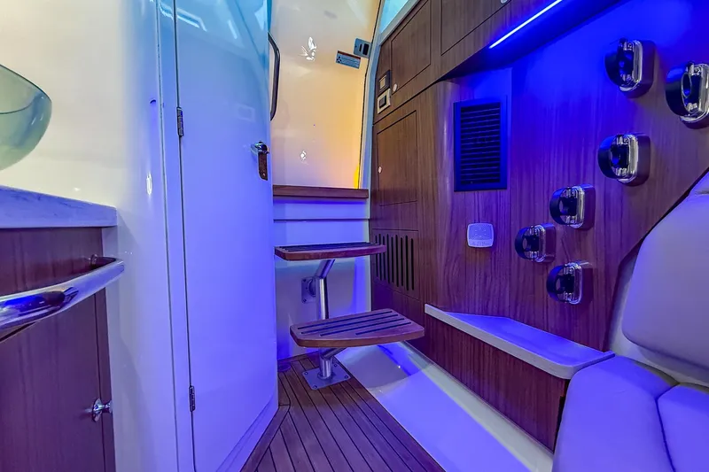 Slide: The Image of Interior of 2022 Boston Whaler 380 Outrage with modern wood finish and blue lighting. - 64