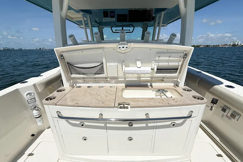 Slide: The Image of 2022 Boston Whaler 380 Outrage boat with open deck storage and sink, on calm water. - 88