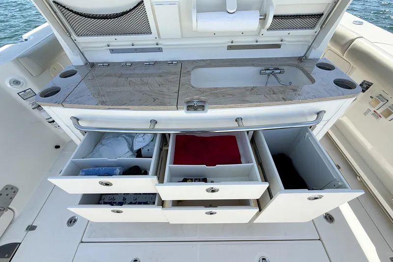 Slide: The Image of 2022 Boston Whaler 380 Outrage boat with open storage drawers and countertop sink. - 92