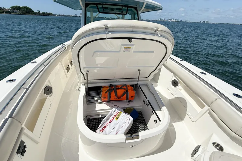 Slide: The Image of 2022 Boston Whaler 380 Outrage boat with open storage compartment, safety gear visible. - 98